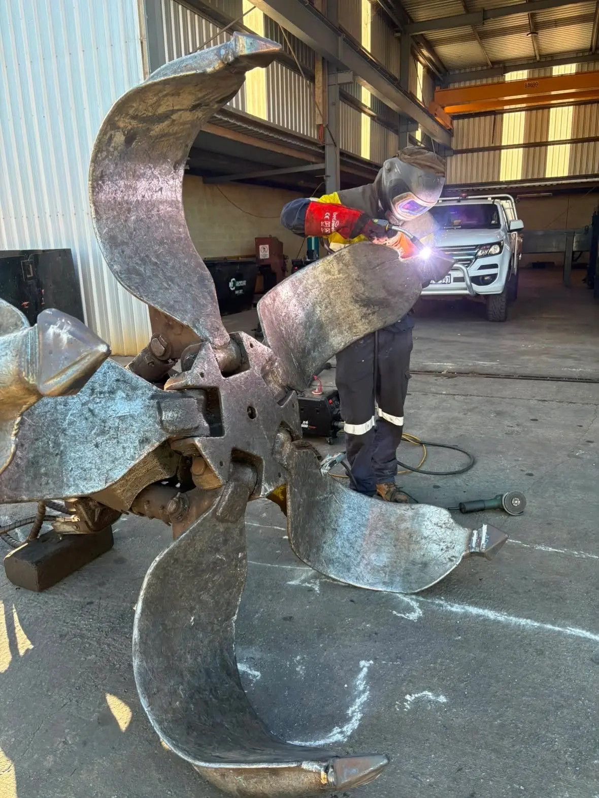 Boilermaker hardfacing the tines of an orange peel grab