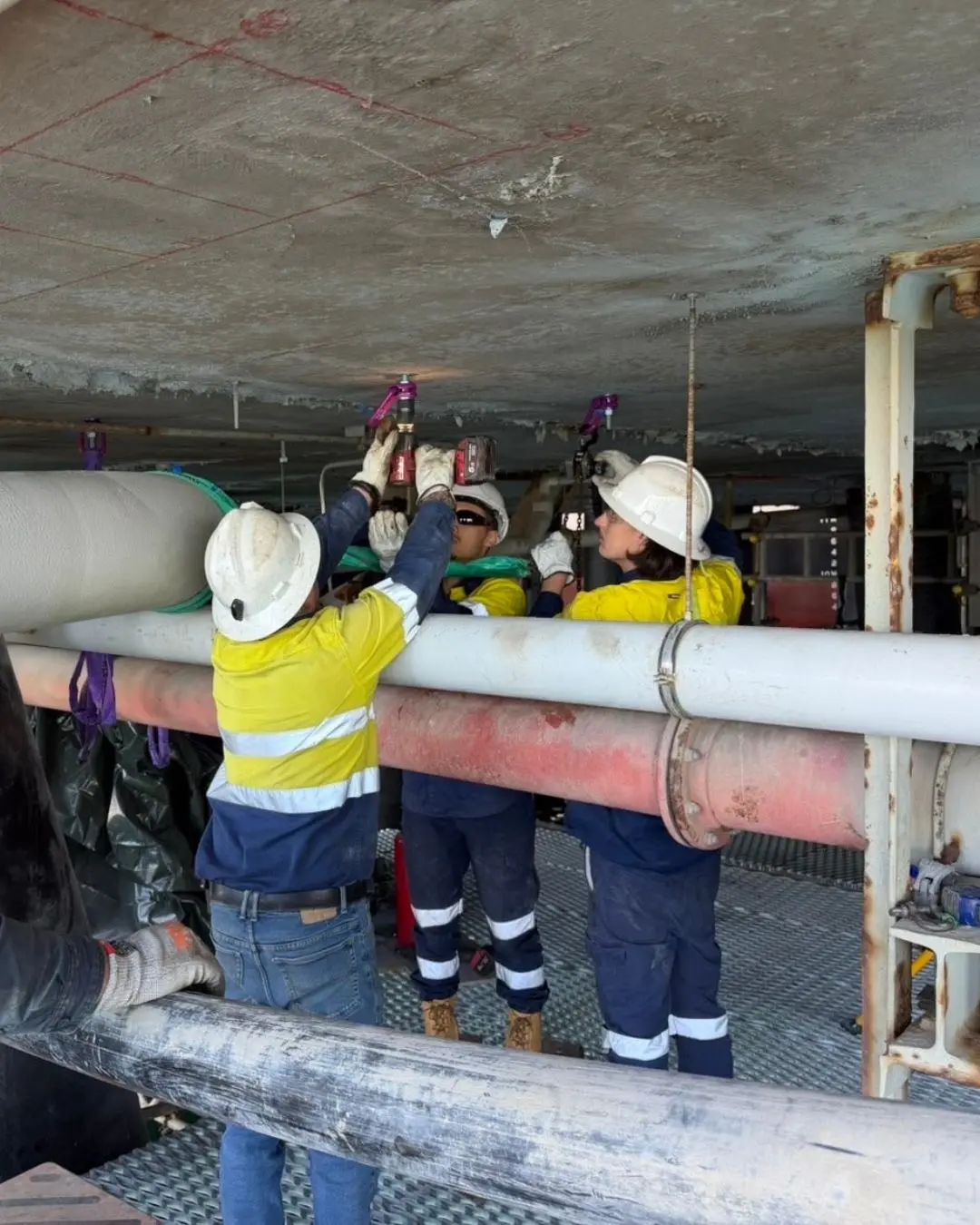 Crew fitting pipe supports under a jetty deck