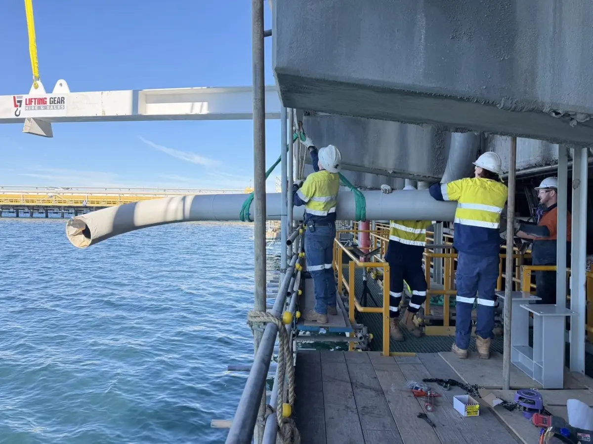 Crew installing a pipe section on a jetty over the water